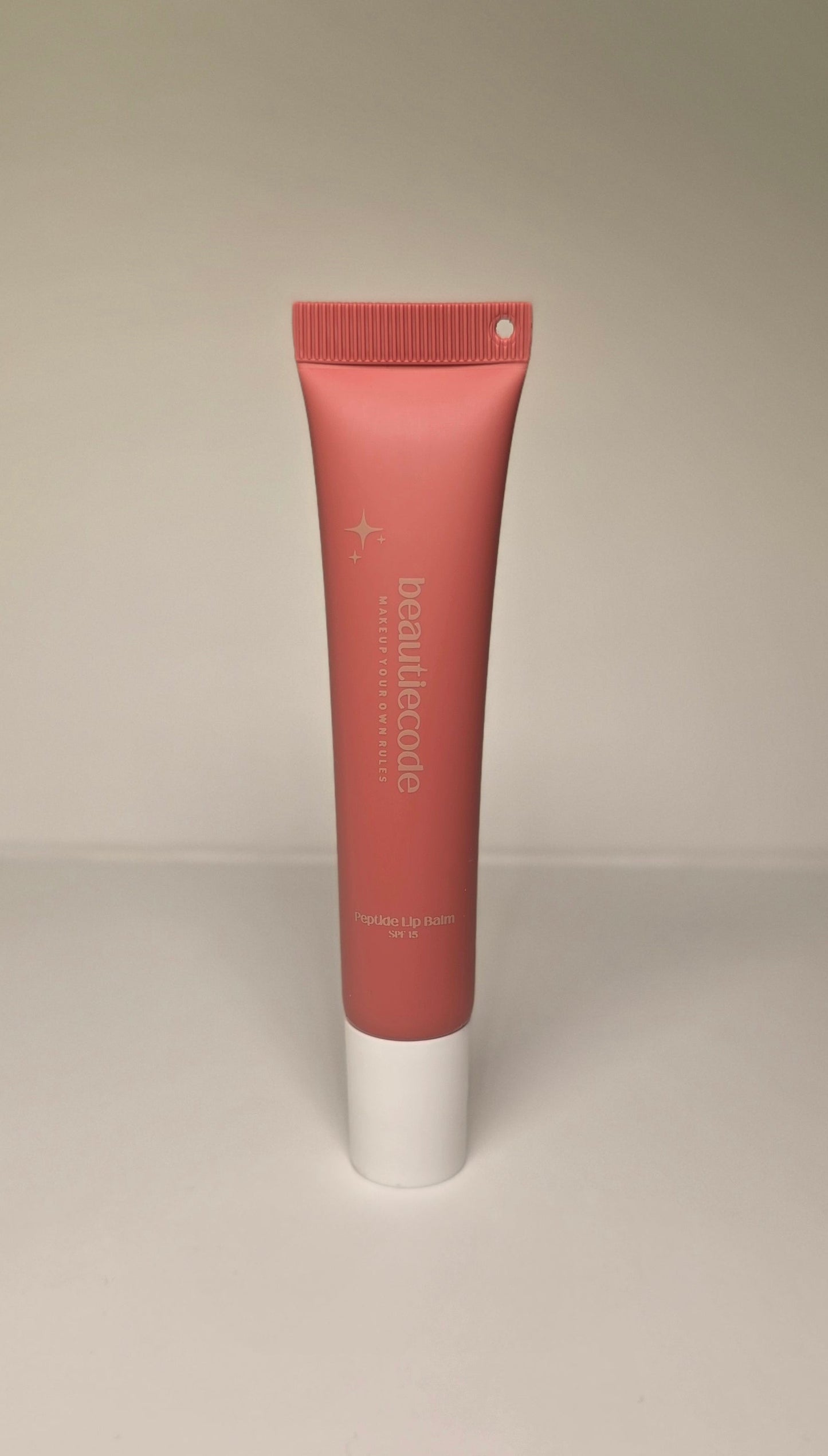 Lip balm tube with a white cap on a beige background
