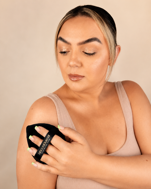 woman holding large powder puff to body showing beautiecode logo on black puff