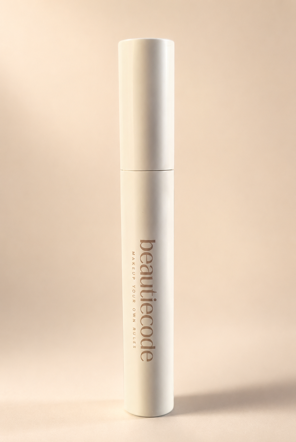 A tall, slim white cosmetic bottle with the brand name 'beautiecode' printed vertically in a muted taupe-brown font, set against a solid, warm beige background.